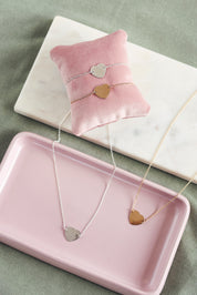 Collier personnalisable Adelie en argent chaîne fine et médaille en forme de cœur à graver - Bijou photographié dans une coupole rectangulaire rose