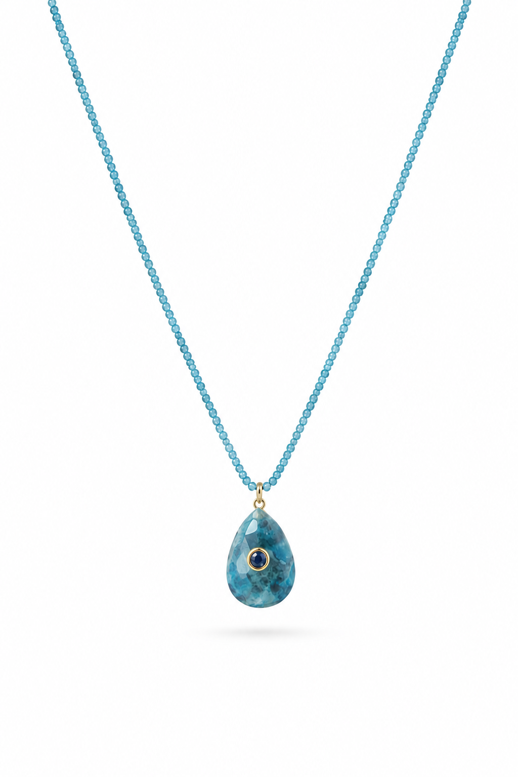 Collier Anthea sur fil doré composé de perles en apatite avec pendentif en forme de goutte orné d'un zircon bleu - Bijou sur fond blanc