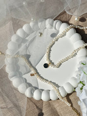 Collier personnalisable Elya doré en nacre pour initiales et charms - Bijou photographié dans une coupole blanche avec un voile de mariée 
