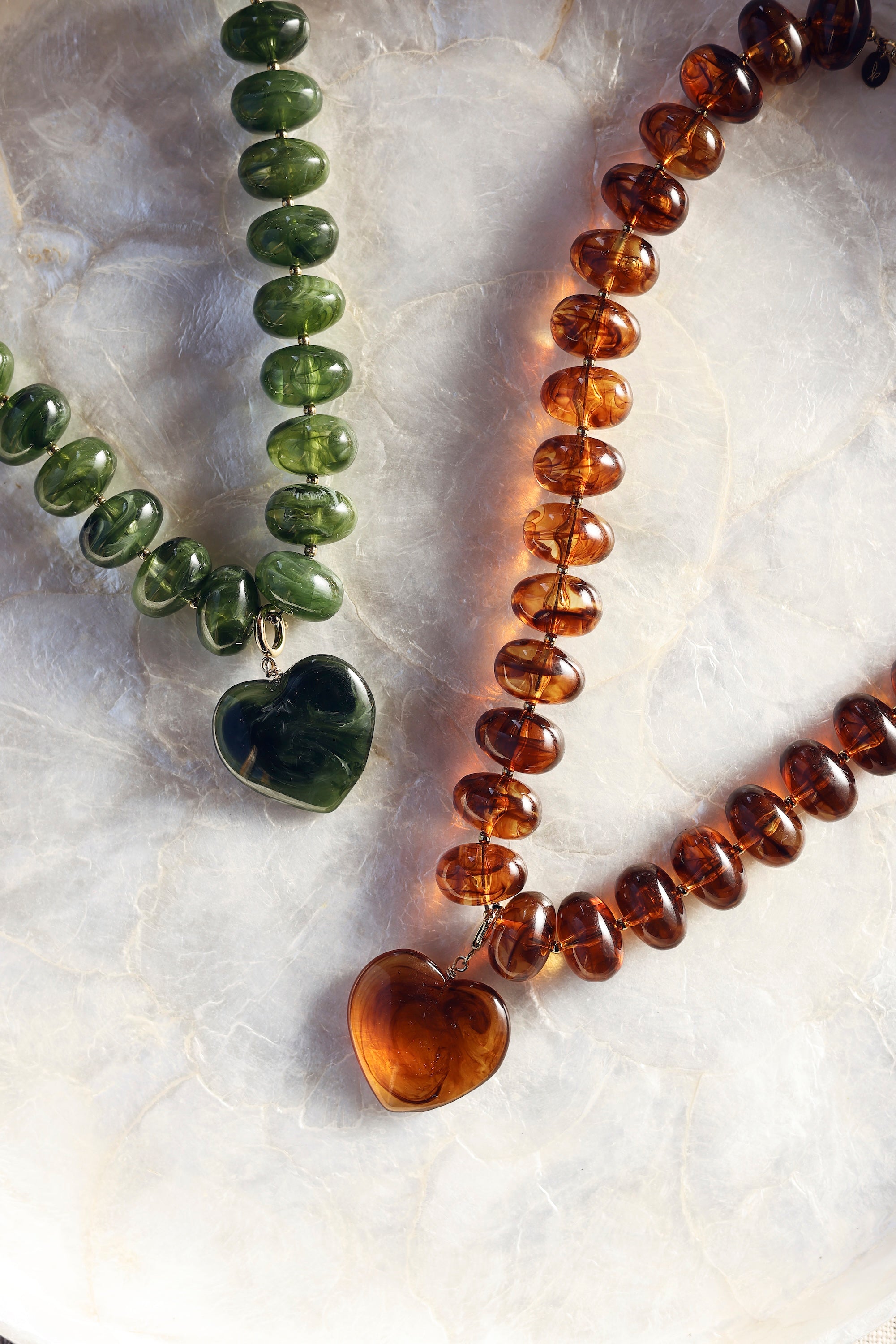 Collier statement doré Ginie brun en acétate avec un pendentif cœur - Bijou photographié sur de la nacre