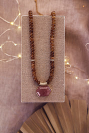Collier statement doré Isis quartz fumé en pierres naturelles et zircons - Bijou photographié sur un présentoir en lin gris
