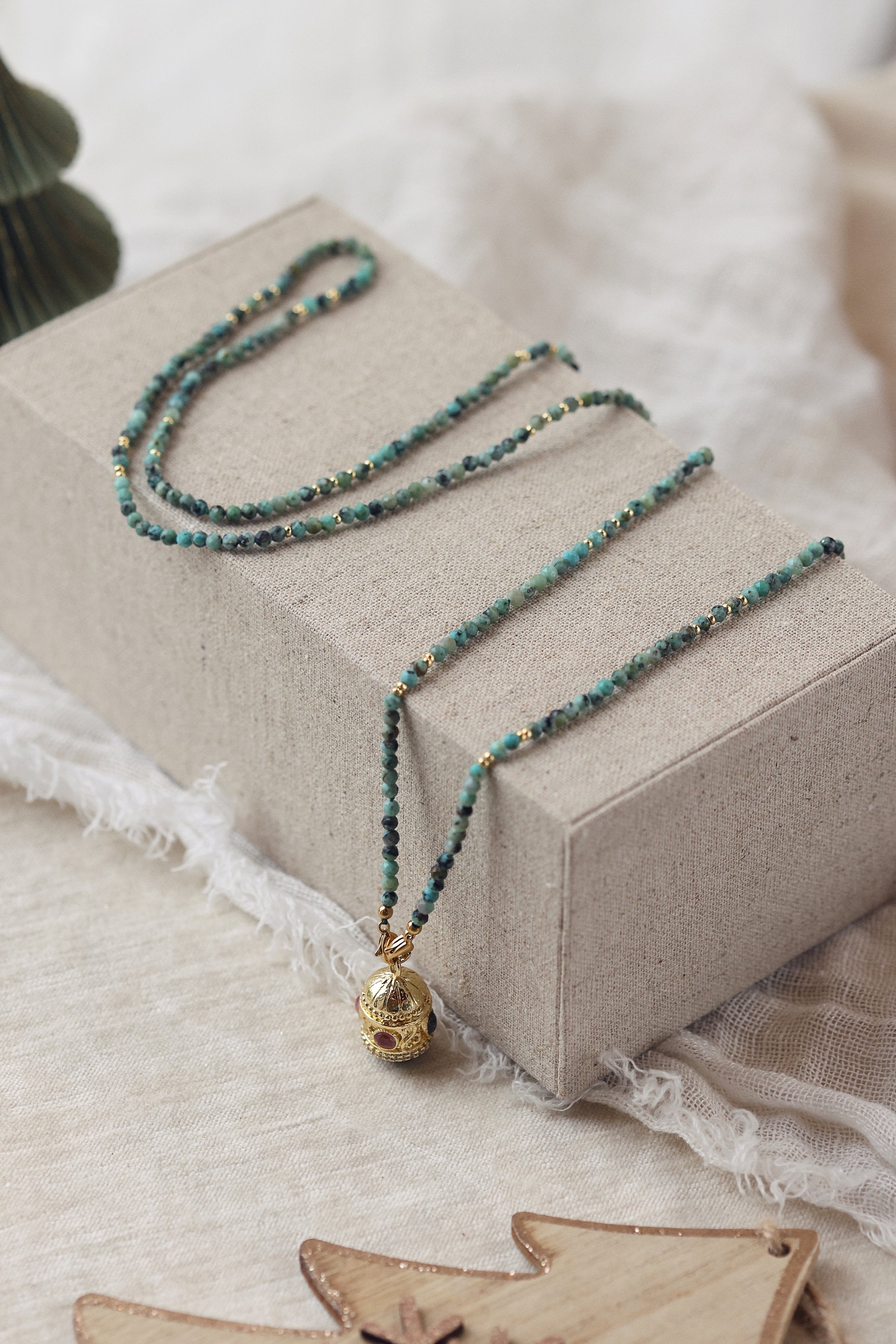 Collier sautoir doré pierres naturelles et pendentif talisman Joe turquoise africaine - Bijou photographié dans un décor de Noël