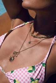 Collier doré Solenia avec anneau torsadé orné de pendentifs hirondelle, soleil orné d'une demi-lune et perle en résine - Bijou porté