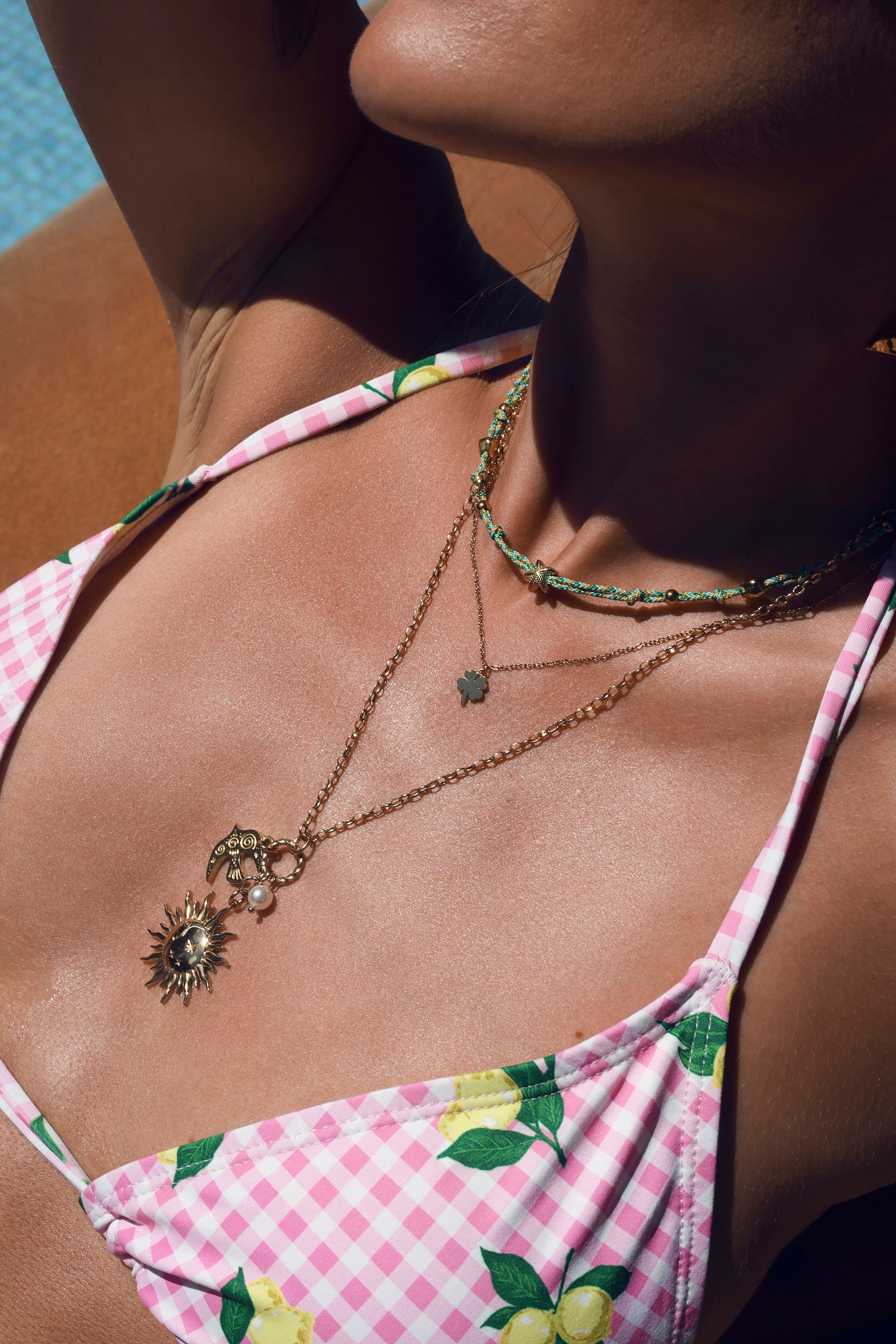 Collier doré Solenia avec anneau torsadé orné de pendentifs hirondelle, soleil orné d'une demi-lune et perle en résine - Bijou porté