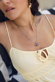 Collier sur fil doré Thelma améthyste composé de perles en améthyste avec pendentif en forme d'œil orné d'une goutte en lapis lazuli - Bijou porté
