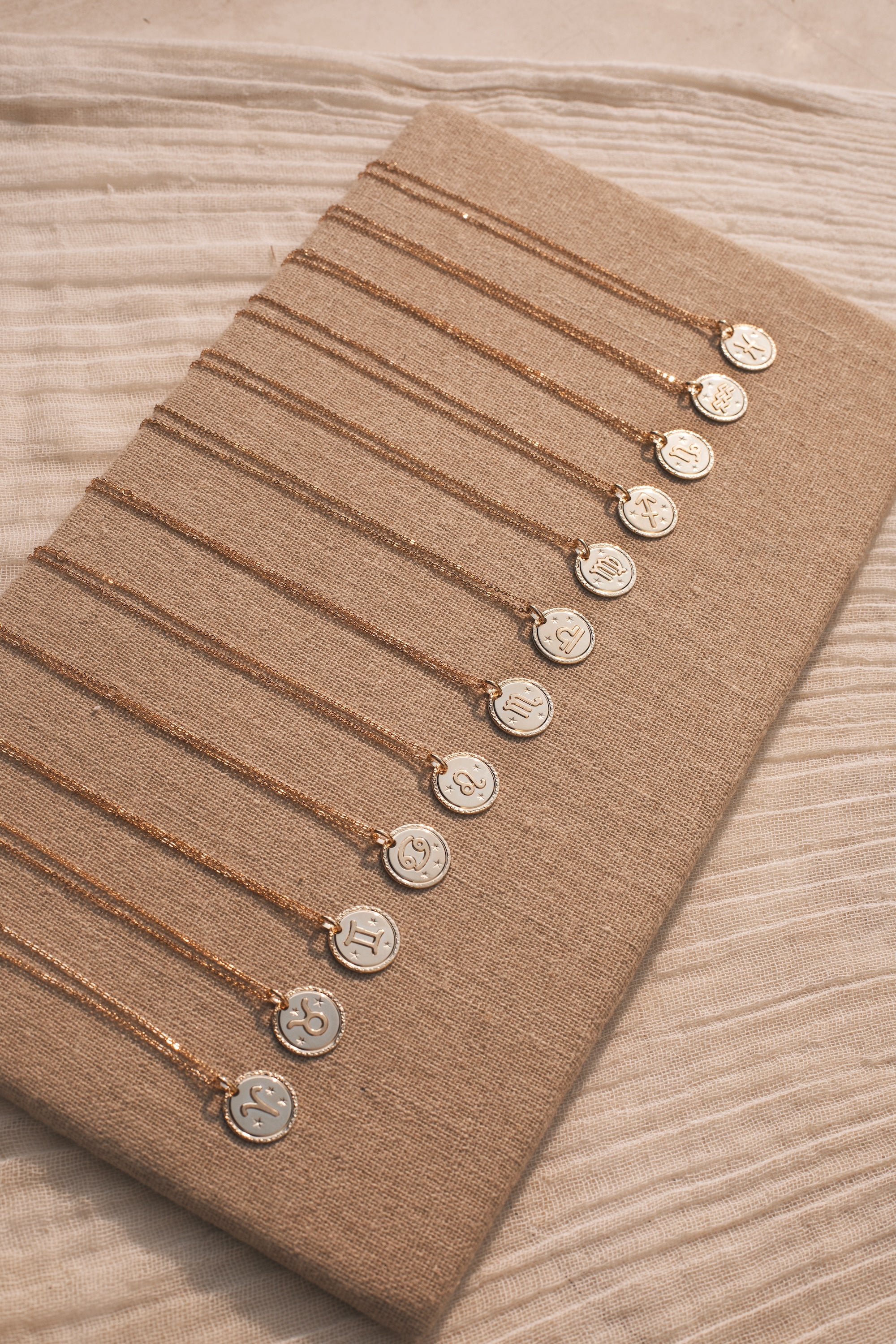  Collier doré signe du zodiaque Balance - Bijou photographié sur planche en lin beige