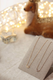 Collier doré Béna - Bijou photographié sur présentoir en lin