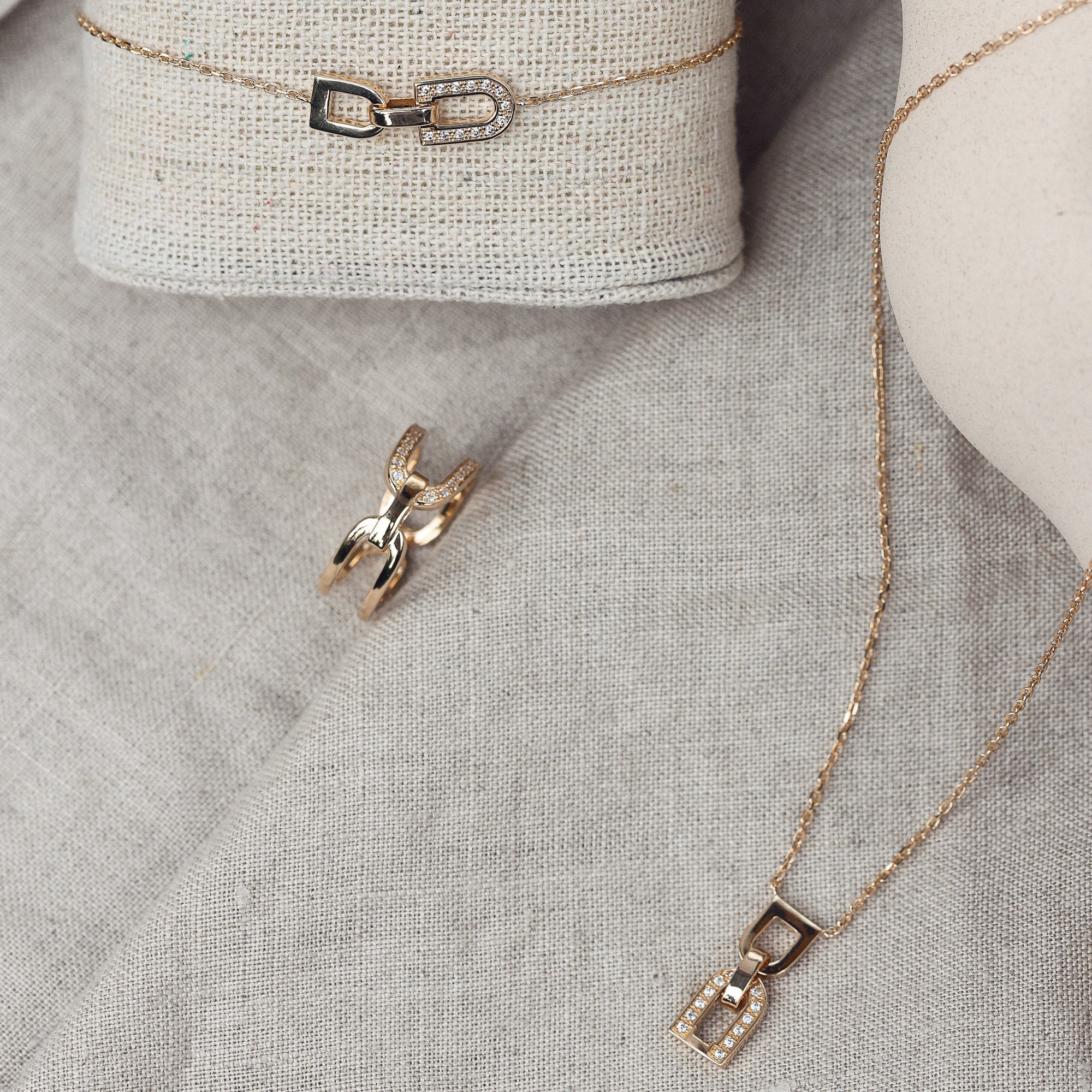 Collier doré Berny pendentif en forme de maille avec zircons - Bijou photographié sur tissu en lin