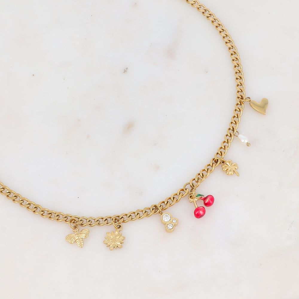 Collier doré CERISE maille avec pendentifs cerises, zircons, nacre, fleur, abeille, trèfle et étoile polaire - Bijou photographié sur fond en marbre blanc