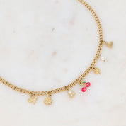 Collier doré CERISE maille avec pendentifs cerises, zircons, nacre, fleur, abeille, trèfle et étoile polaire - Bijou photographié sur fond en marbre blanc