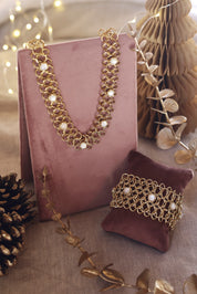 Collier statement doré Dolli en maille épaisse orné de nacres - Bijou photographié sur un présentoir en velours rose foncé avec des décorations de Noël