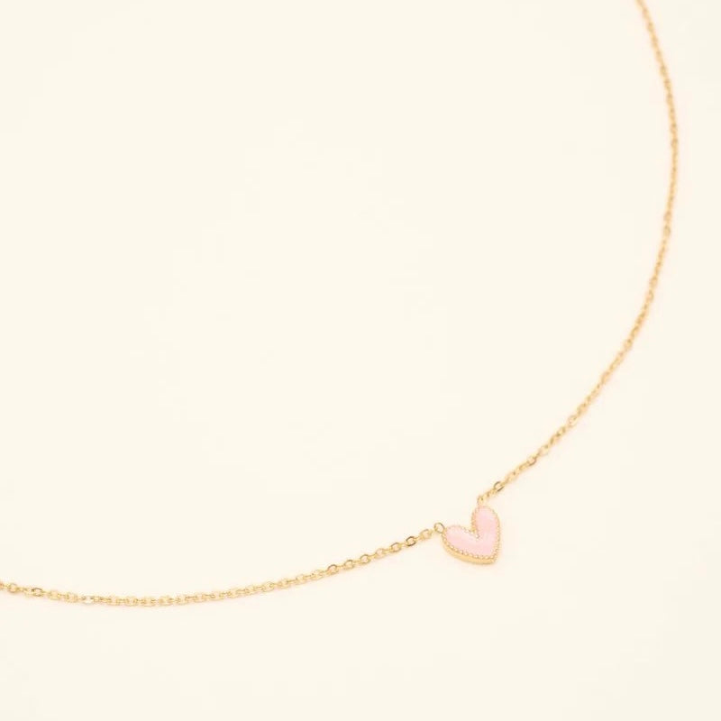Collier Petit Coeur pour enfant doré pendentif coeur rose clair - Bijou photographié sur fond beige