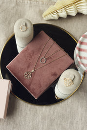 Collier doré Enora pendentif anneau orné de zircons - Bijou photographié sur un présentoir en velours rose foncé posé sur un miroir