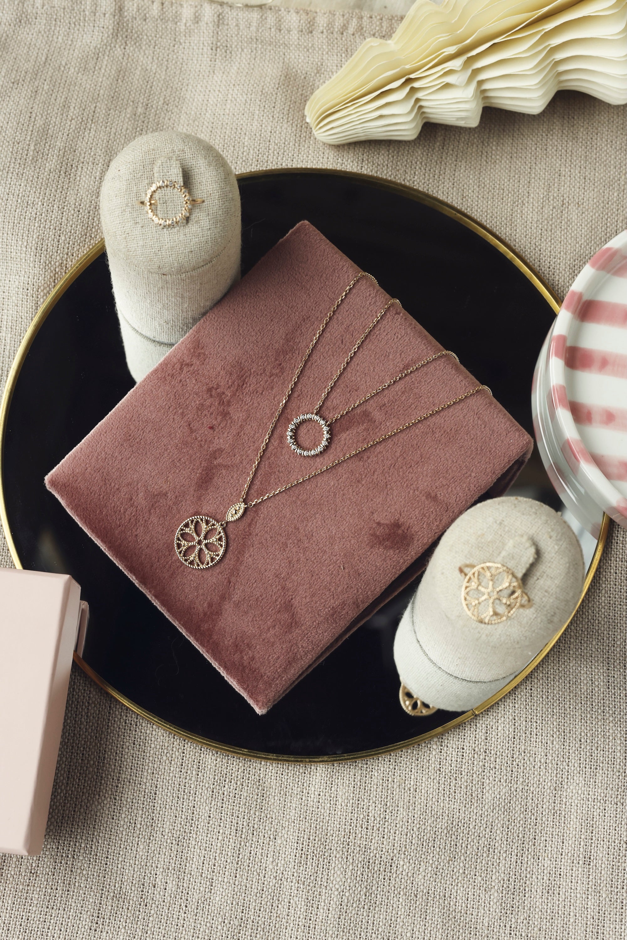 Collier doré Enora pendentif anneau orné de zircons - Bijou photographié sur un présentoir en velours rose foncé posé sur un miroir