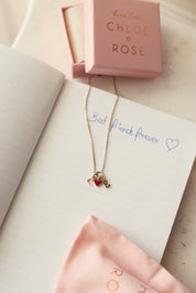 Collier doré Lilou passion personnalisable anneau avec pendentif cœur rouge pour lettre alphabet et charms - Bijou photographié sur un livre