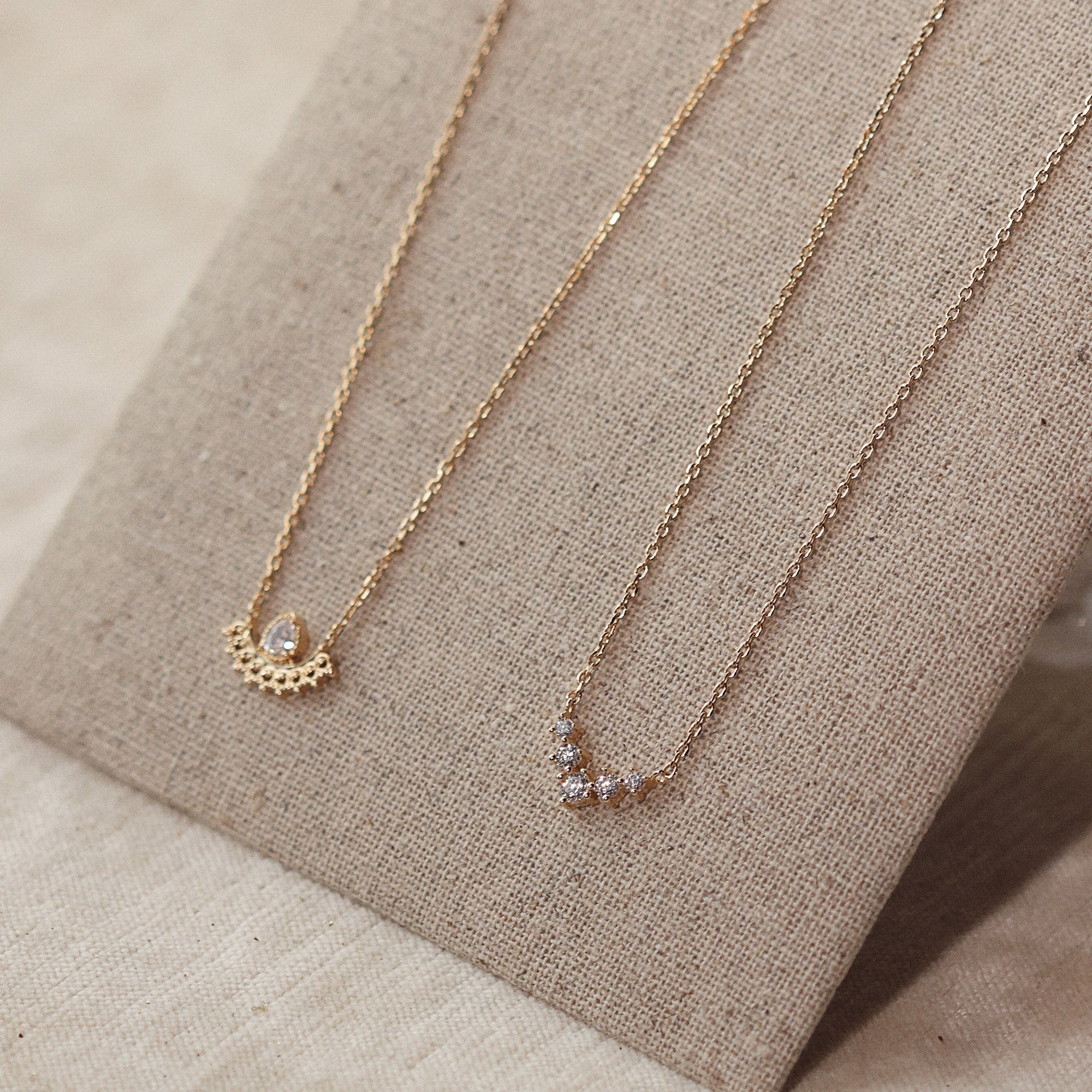 Collier doré Madysson en plaqué or avec pendentif contemporain, collection Chloé Rose Genève - Bijou photographié sur présentoir en lin gris