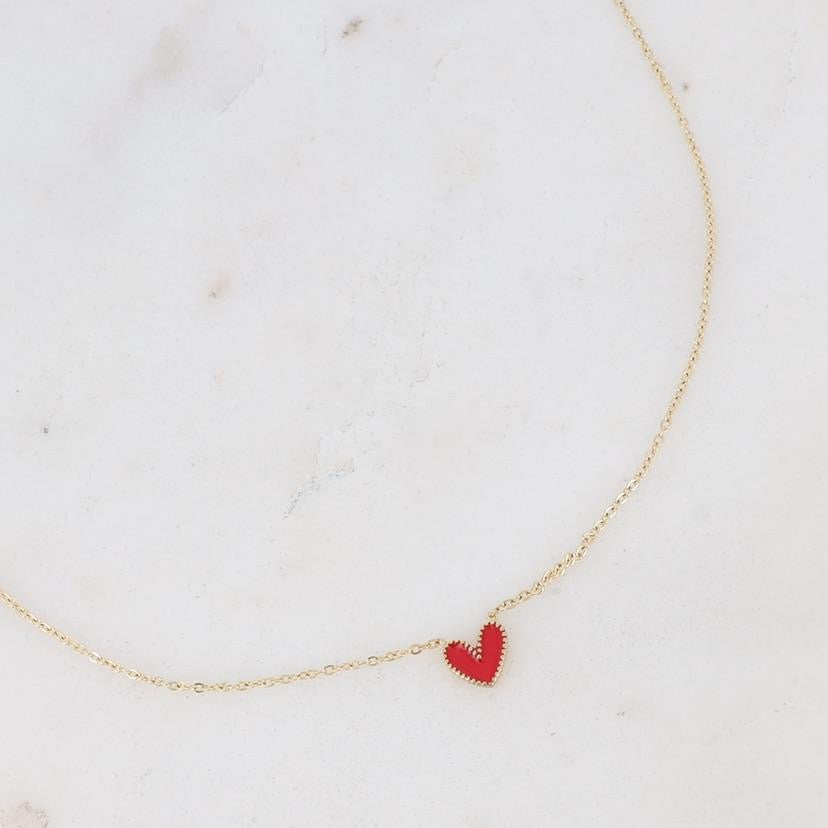 Collier Petit coeur pour enfant doré pendentif coeur rouge - Bijou photographié sur fond beige