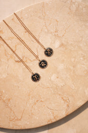  Collier doré signe du zodiaque Sagittaire - Bijou photographié sur pierre marbrée de couleur beige