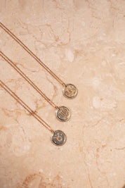 Collier doré signe du zodiaque Vierge - Bijou photographié sur pierre en marbre beige