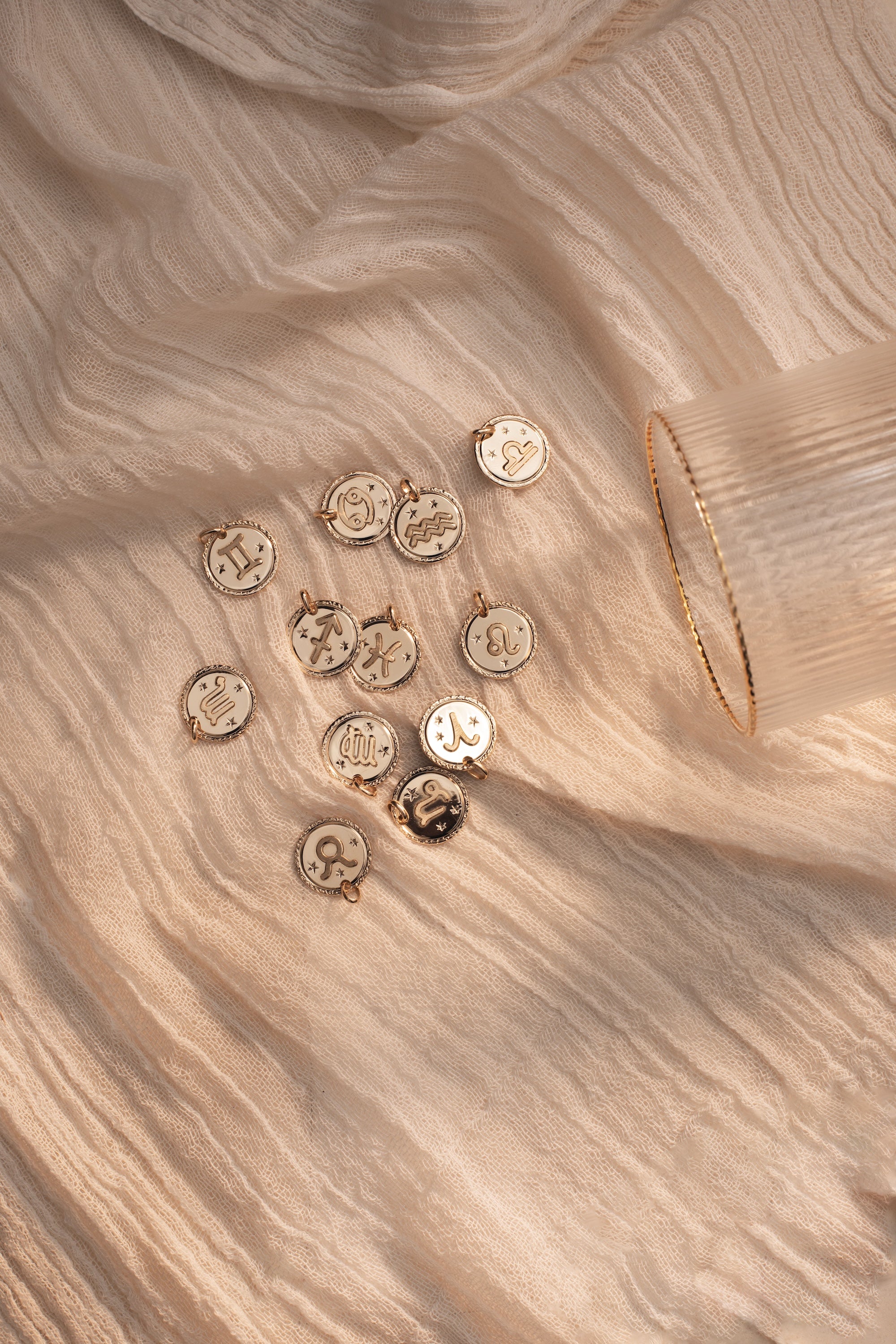 Collier doré signe du zodiaque Lion - Bijou photographié sur tissu blanc crème