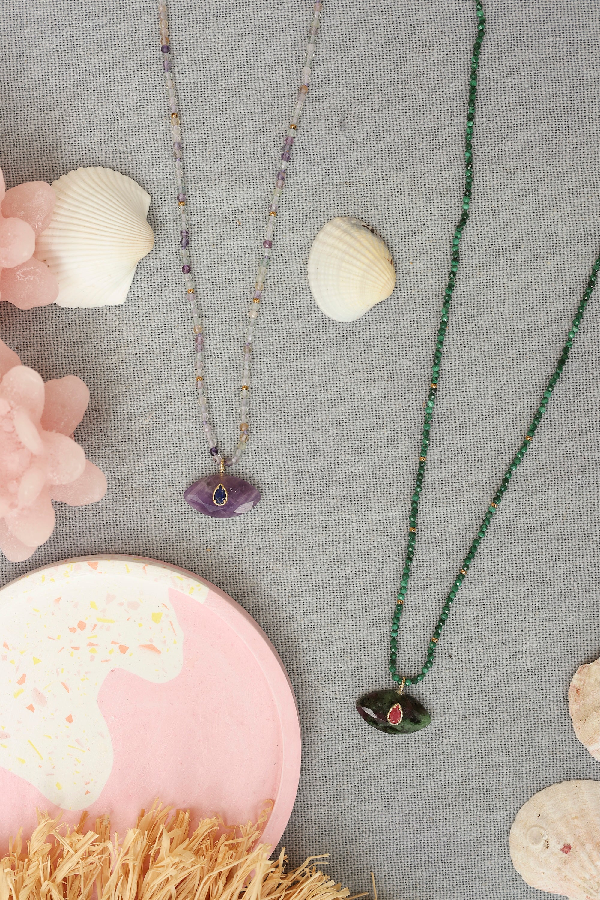 Collier sur fil doré Thelma malachite composé de perles en malachite avec pendentif en forme d'œil en rubis zoïsite orné d'une goutte en rhodonite - Bijou photographié dans un décor estival