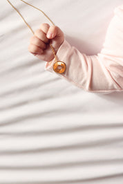 Collier personnalisable doré Isao chaîne fine et médaille cible à graver - Bijou porté dans la main d'un bébé