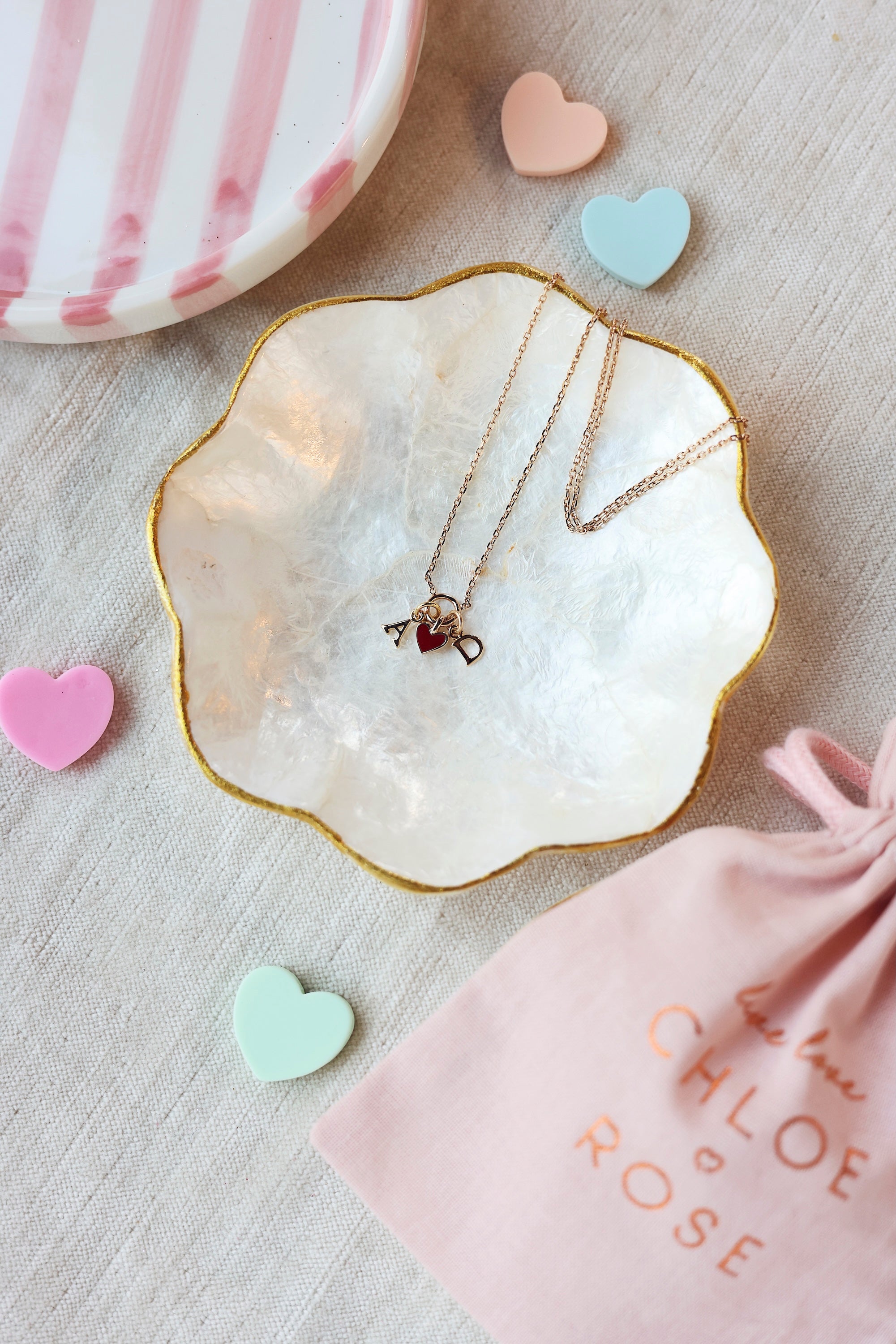 Collier doré Lilou passion personnalisable avec pendentif cœur rouge - Bijou photographié dans une coupole en nacre dans une ambiance saint valentin