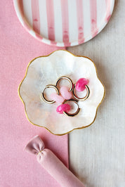 Boucles d'oreilles Benida rose créoles dorées avec pendentif donut rose - Bijou photographié dans une coupole en nacre aux bords dorés 