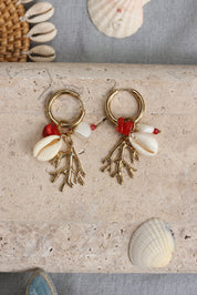 Boucles d'oreilles mini créoles dorées Lowen avec pendentifs corail, coquillage et pierres naturelles - Bijou photographié dans un décor estival