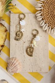 Mini créoles dorées Nelly pendentifs coquillages, poisson, étoile de mer - Bijou photographié dans un décor estival