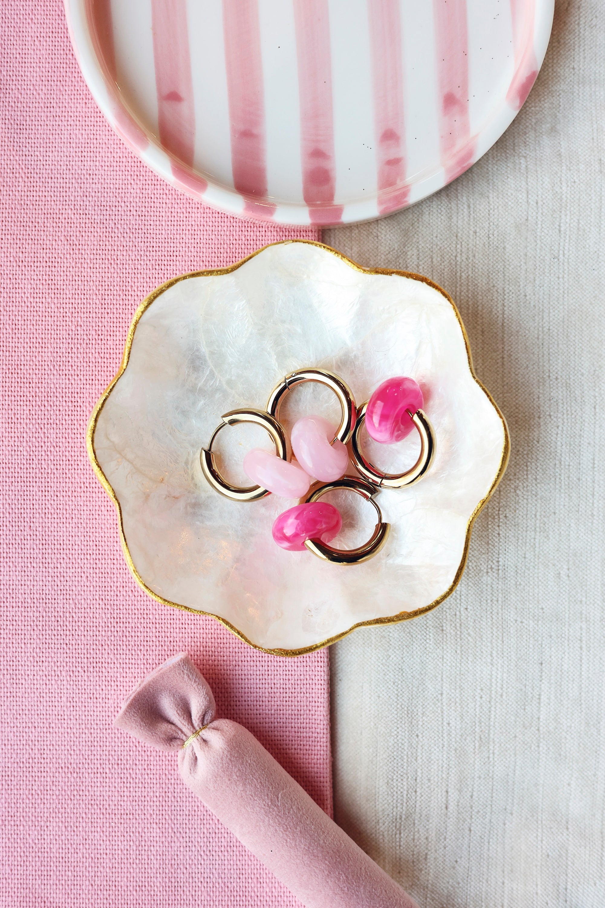 Boucles d'oreilles Benida fuchsia créoles dorées avec pendentif donut rose fuchsia - Bijou photographié dans une coupole en nacre aux bords dorés