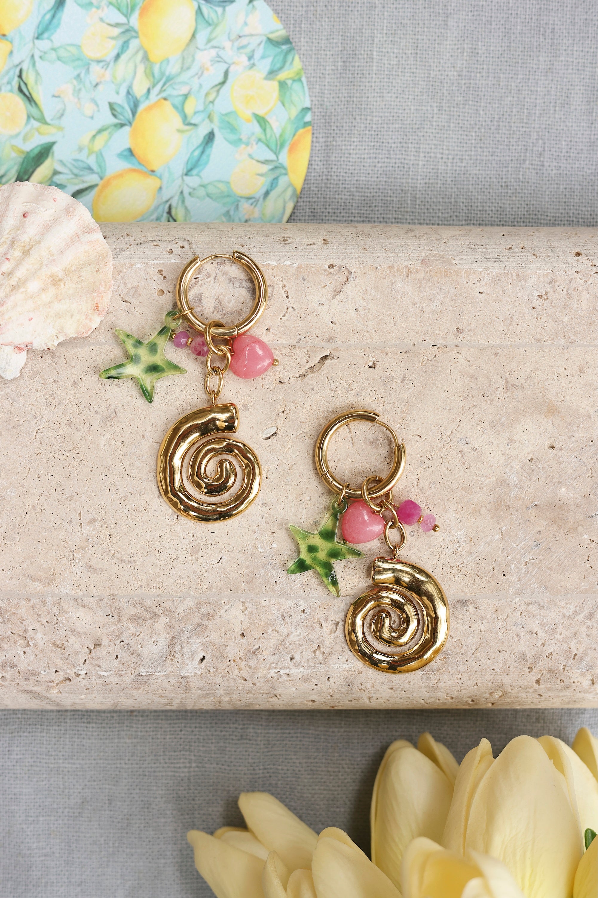Boucles d'oreilles mini créoles dorées Jezabel avec pendentifs escargot, cœur et étoile de mer - Bijou dans un décor estival
