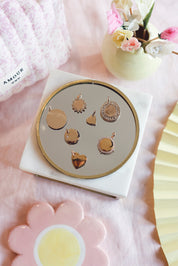 Médaille dorée Amour XS en forme de cœur pour gravure - Bijou photographié sur un miroir rond avec d'autres médailles