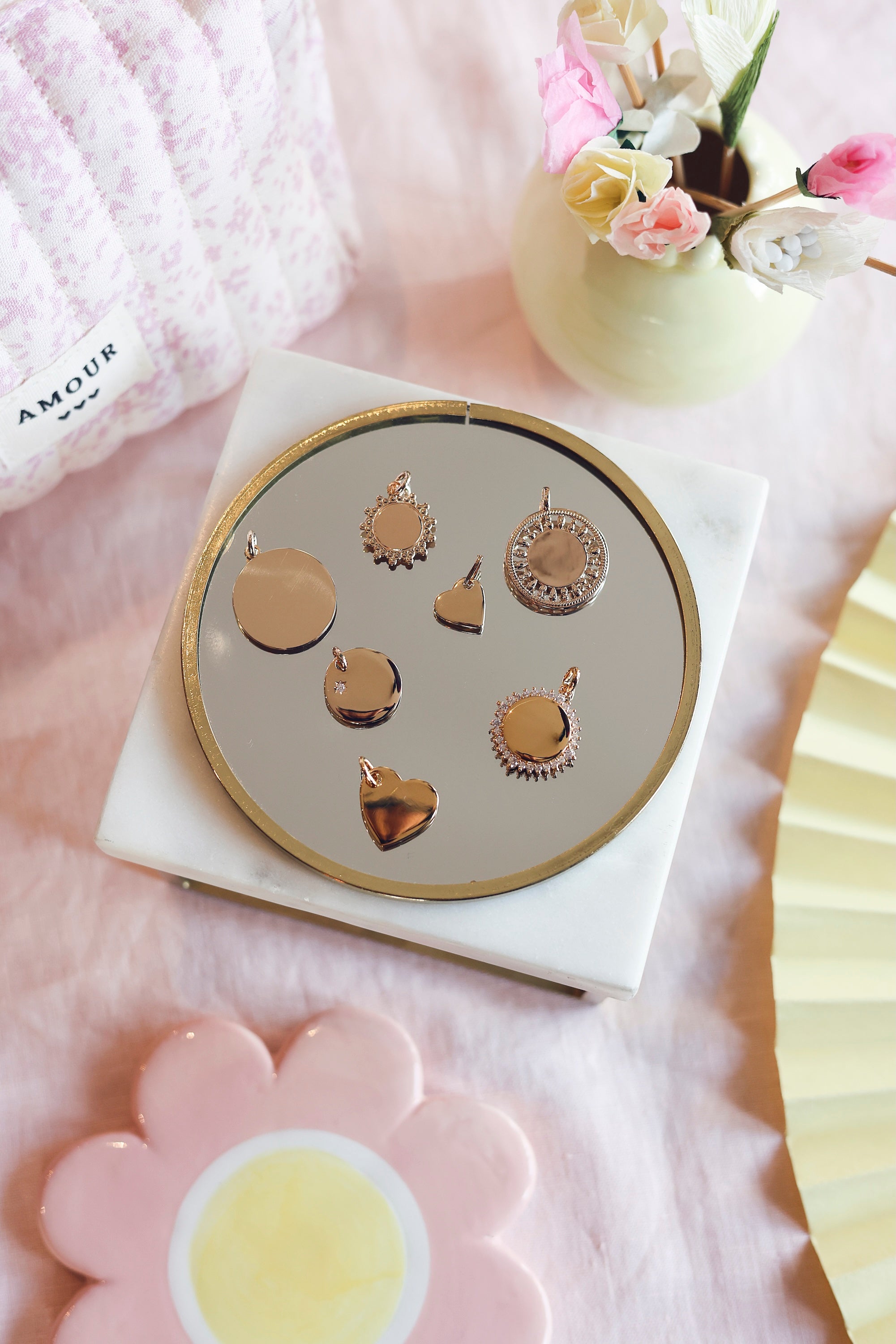 Médaille dorée Amour XS en forme de cœur pour gravure - Bijou photographié sur un miroir rond avec d'autres médailles