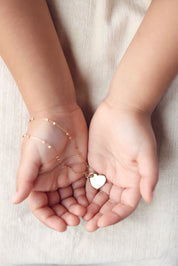 Médaille dorée Amour S en forme de cœur pour gravure - Bijou porté dans les mains d'une enfant