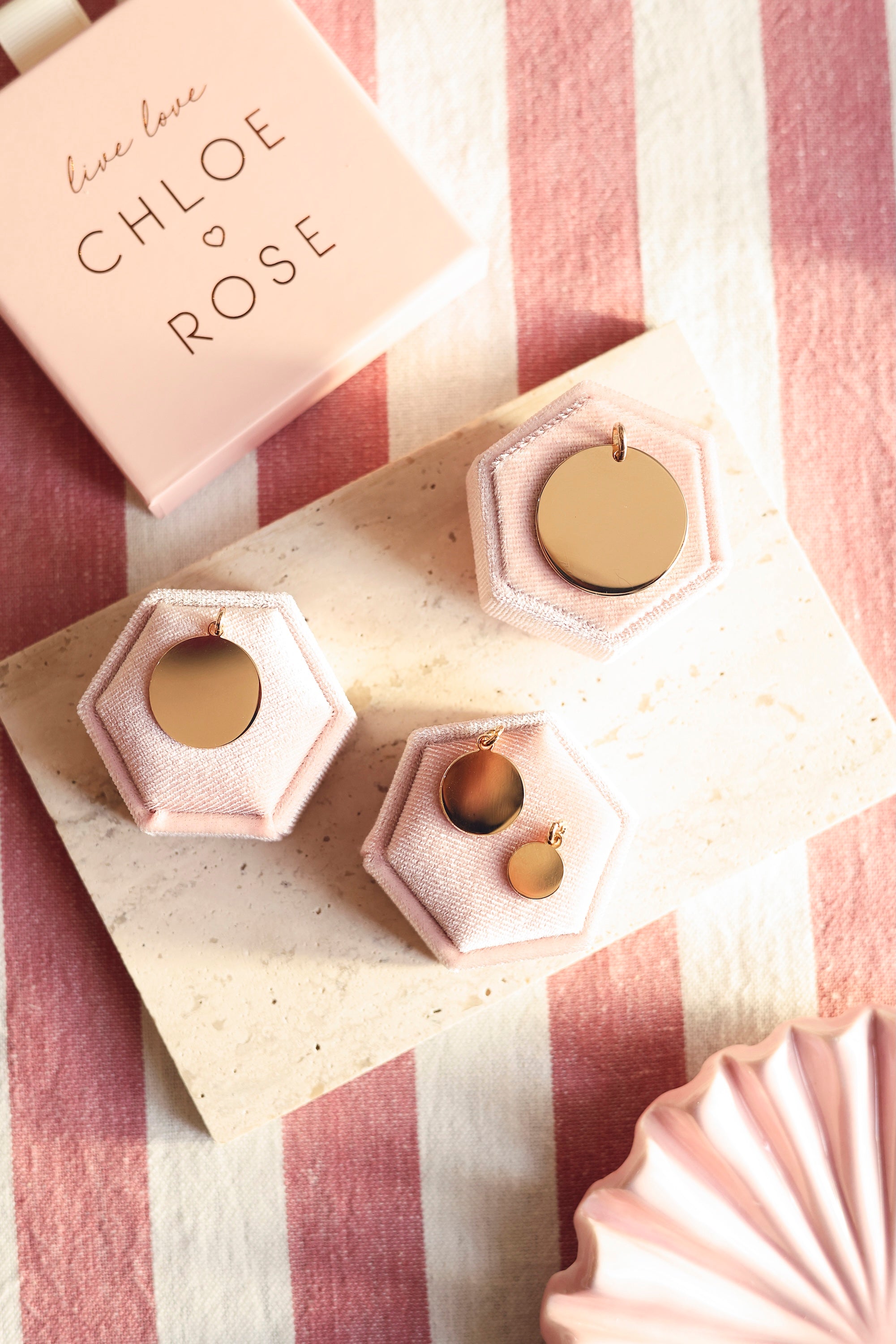 Médaille ronde simple dorée pour gravure Alba S - Bijou photographié sur une pierre blanche posée sur un tissu rayé rose et blanc