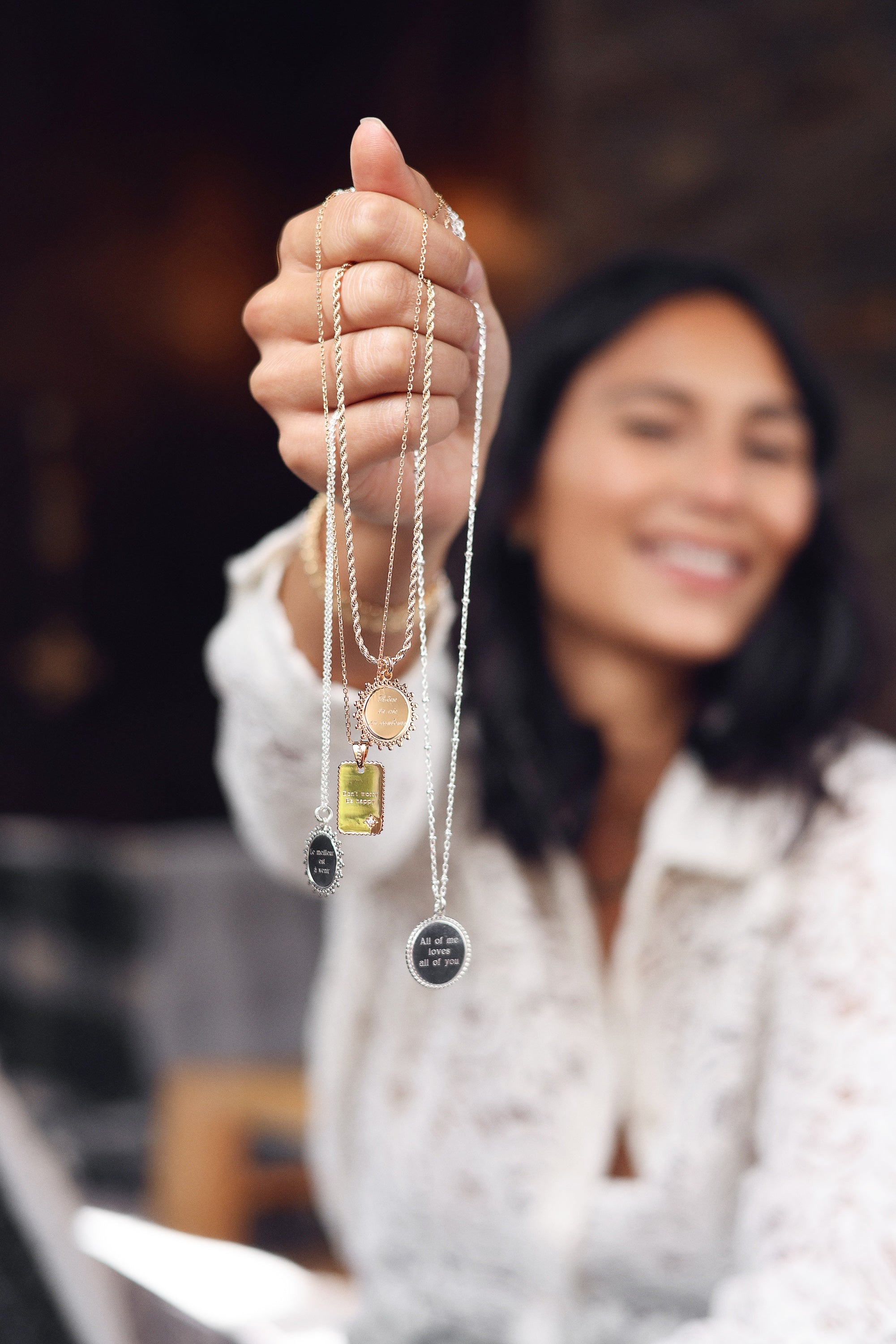 Médaille rectangulaire dorée Emilie avec bordure ondulée ornée d'une étoile zircon - Bijou porté dans une main