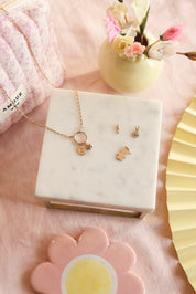 Charm doré zircons Fleur blanc - Bijou photographié sur un présentoir en marbre blanc