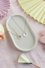 Pendentif rond en nacre à personnaliser avec lettre de l'alphabet ou charm - Bijou photographié dans une coupole blanche 