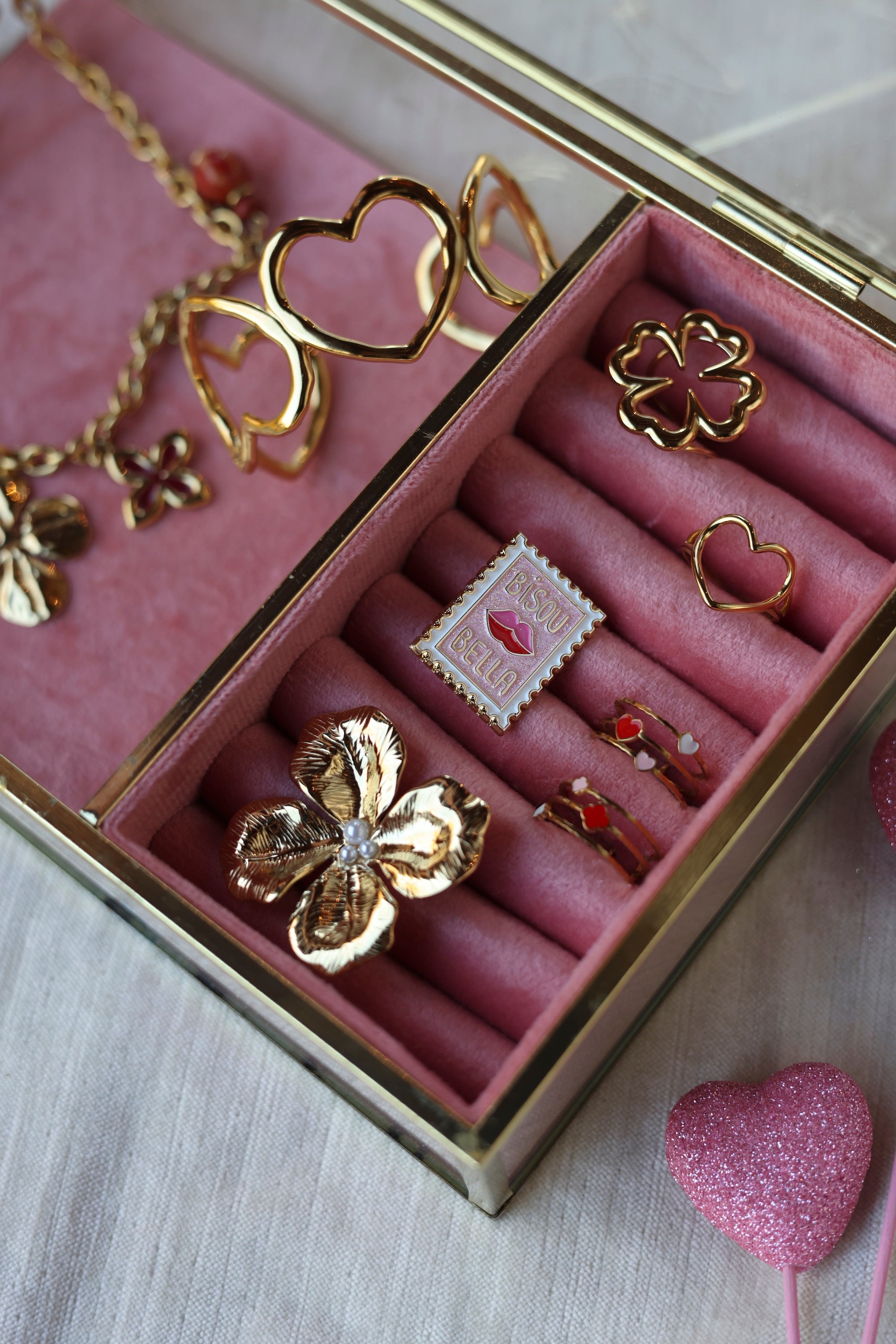 Pin's doré timbre - Accessoire photographié dans une boite à bijoux en velours rose